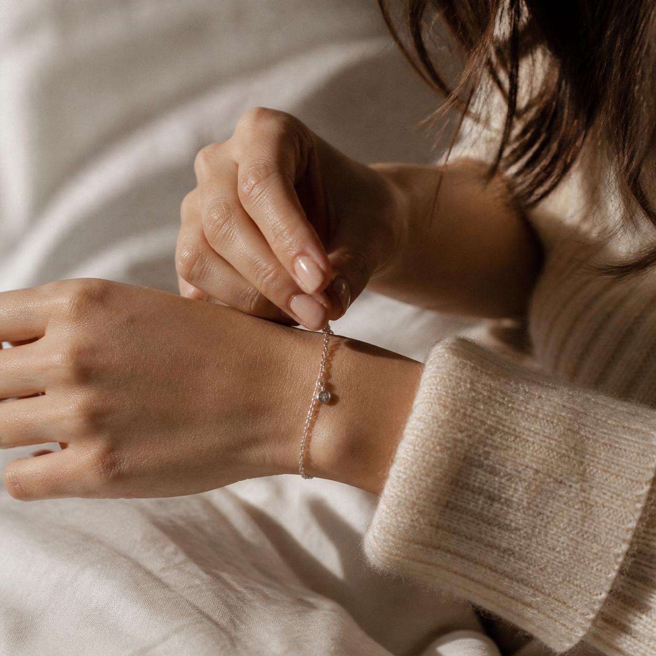 Woman fastening a delicate silver bracelet